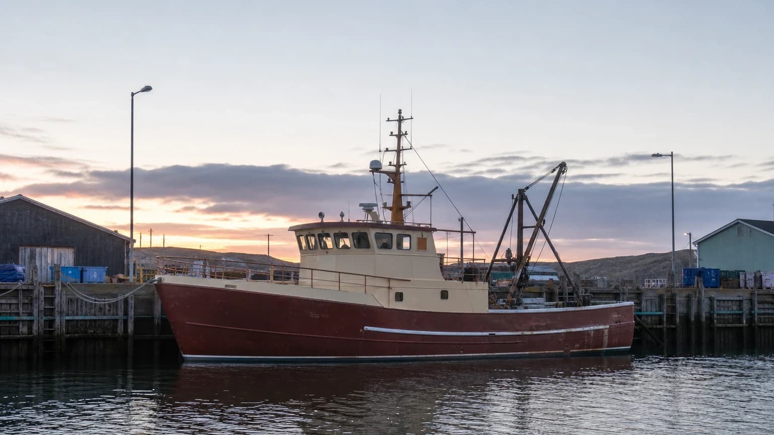 Commercial fishing vessel docked in a working harbor at dawn